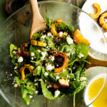 A roasted squash salad made with spinach in a bowl.