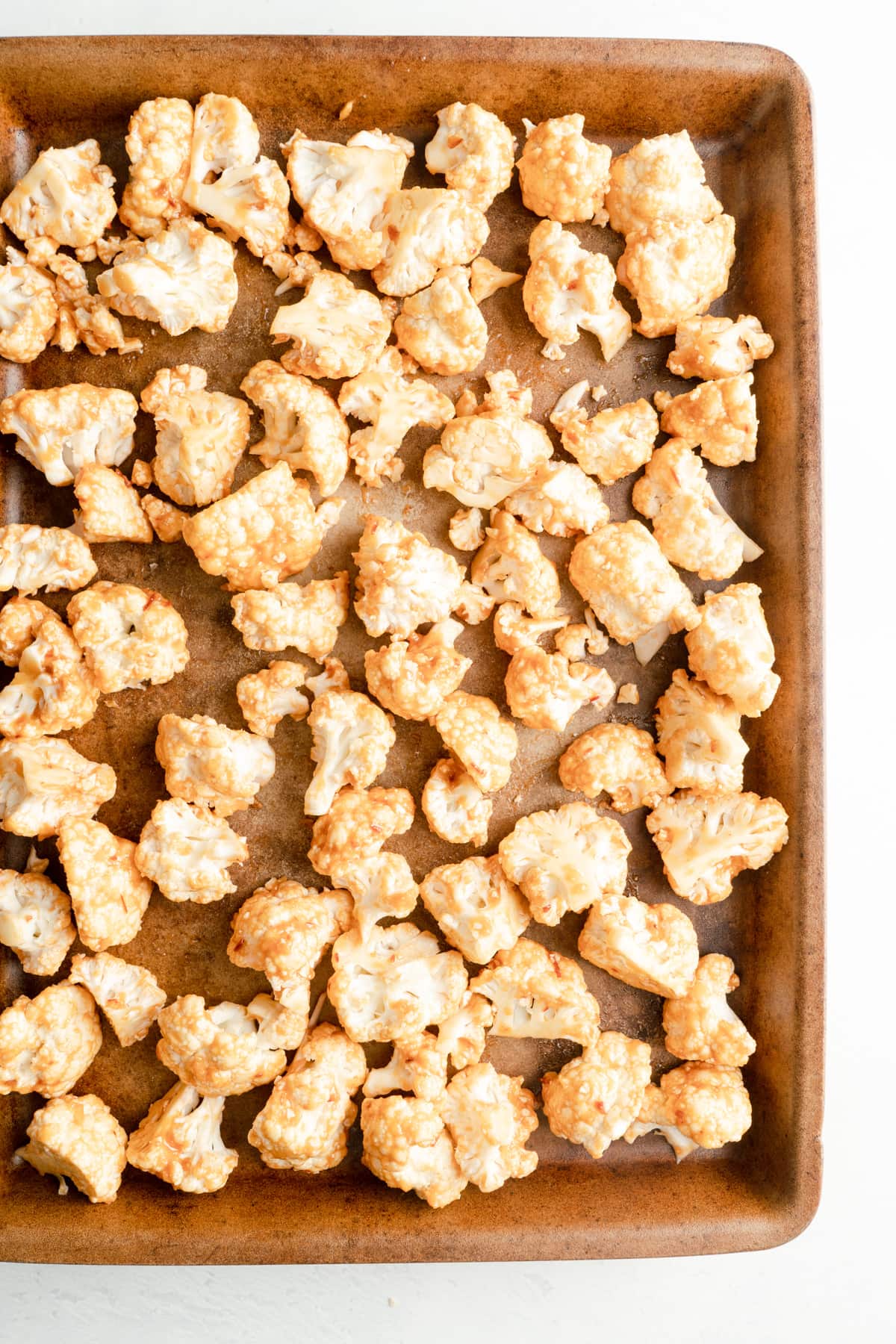 Cauliflower florets on a baking sheet covered in a miso marinade.