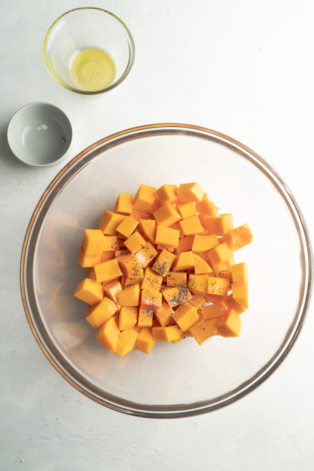 A bowl of butternut squash being seasoned.