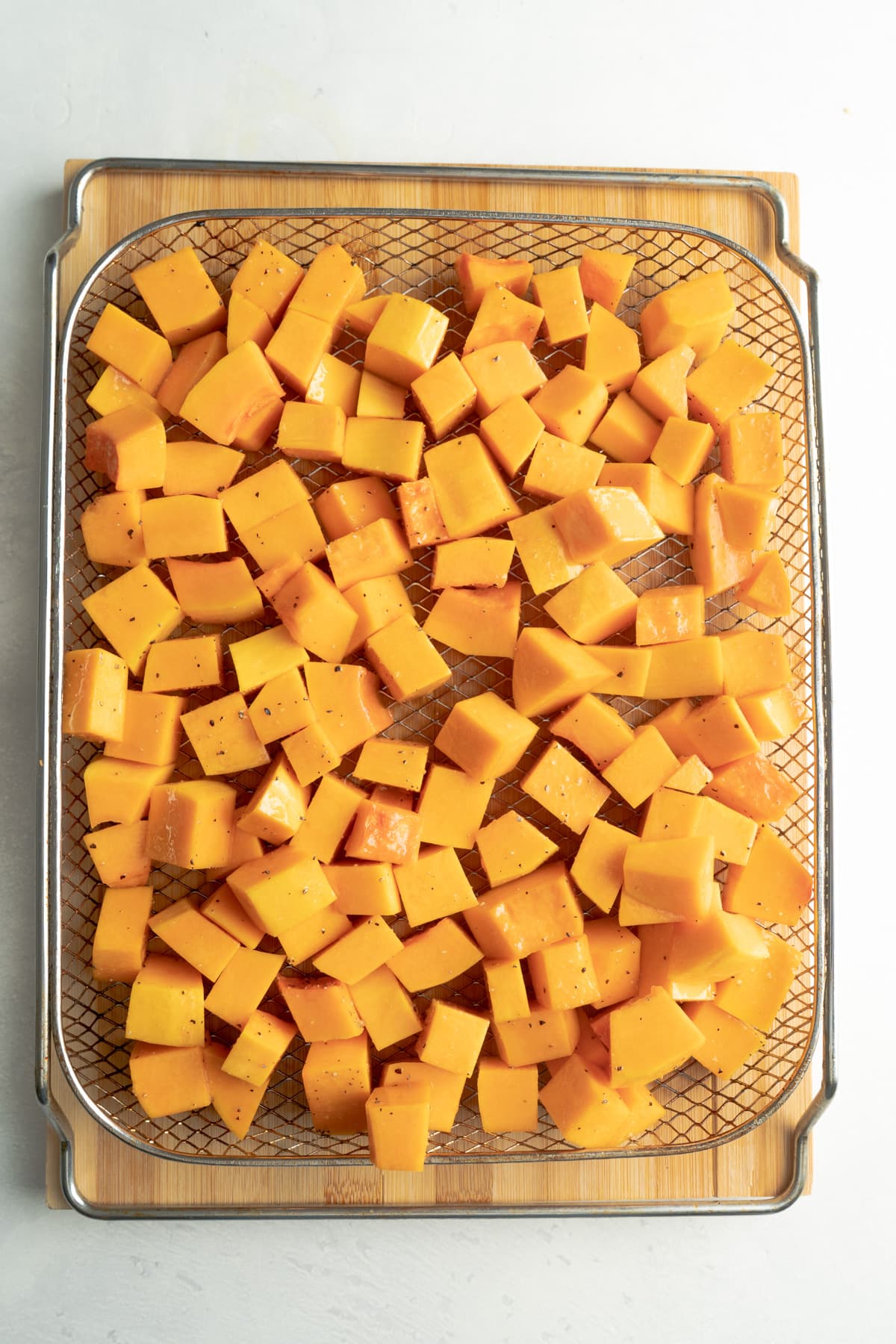 Preparing Butternut squash in air fryer basket.