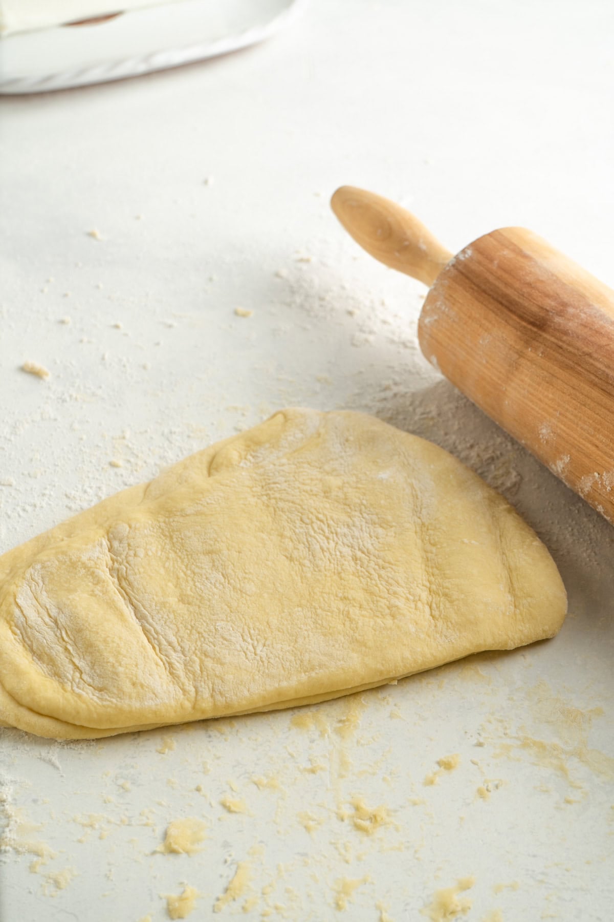 Angel wing pastry being rolled out and hit with a rolling pin.