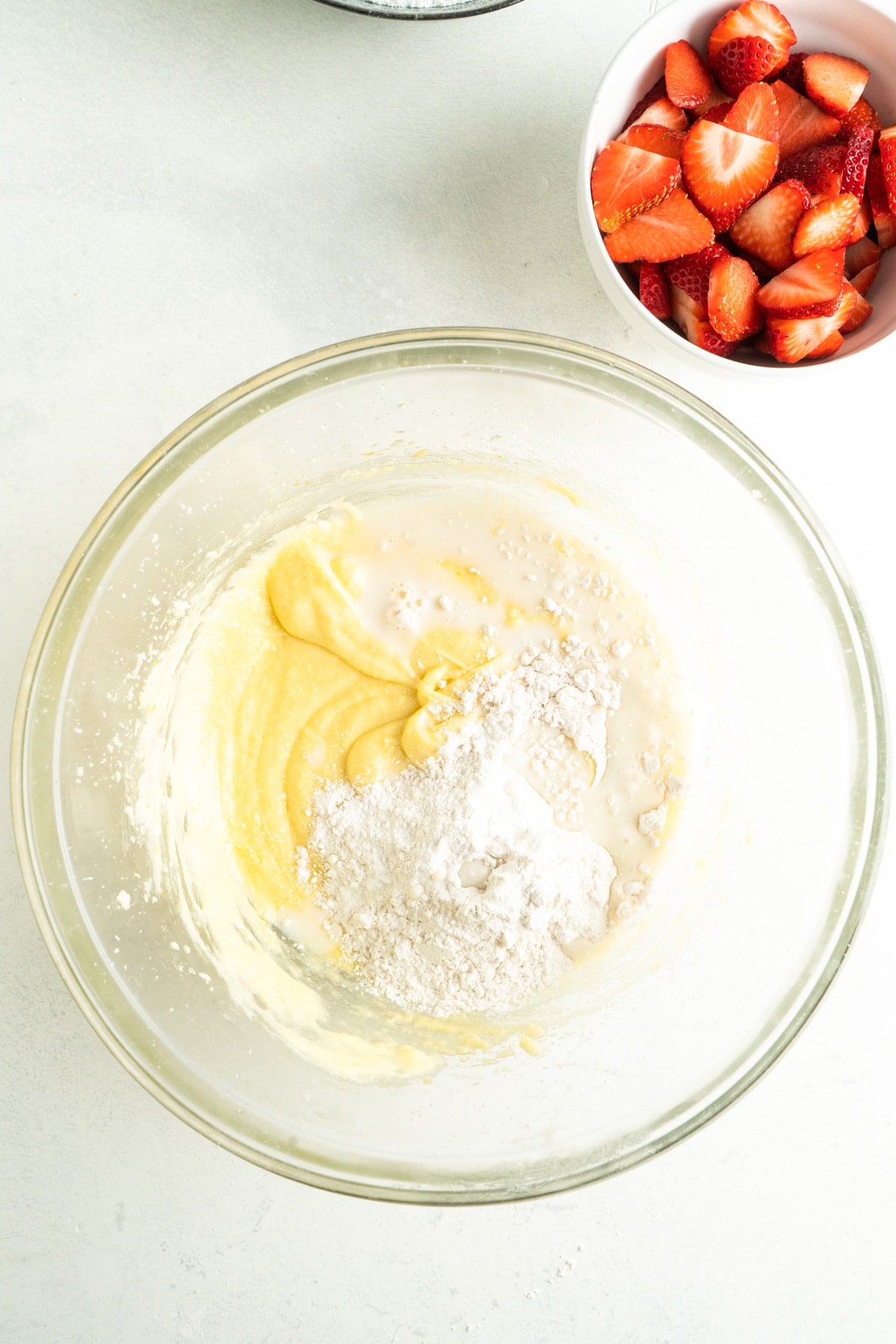 Flour being added to cupcake batter in a bowl.