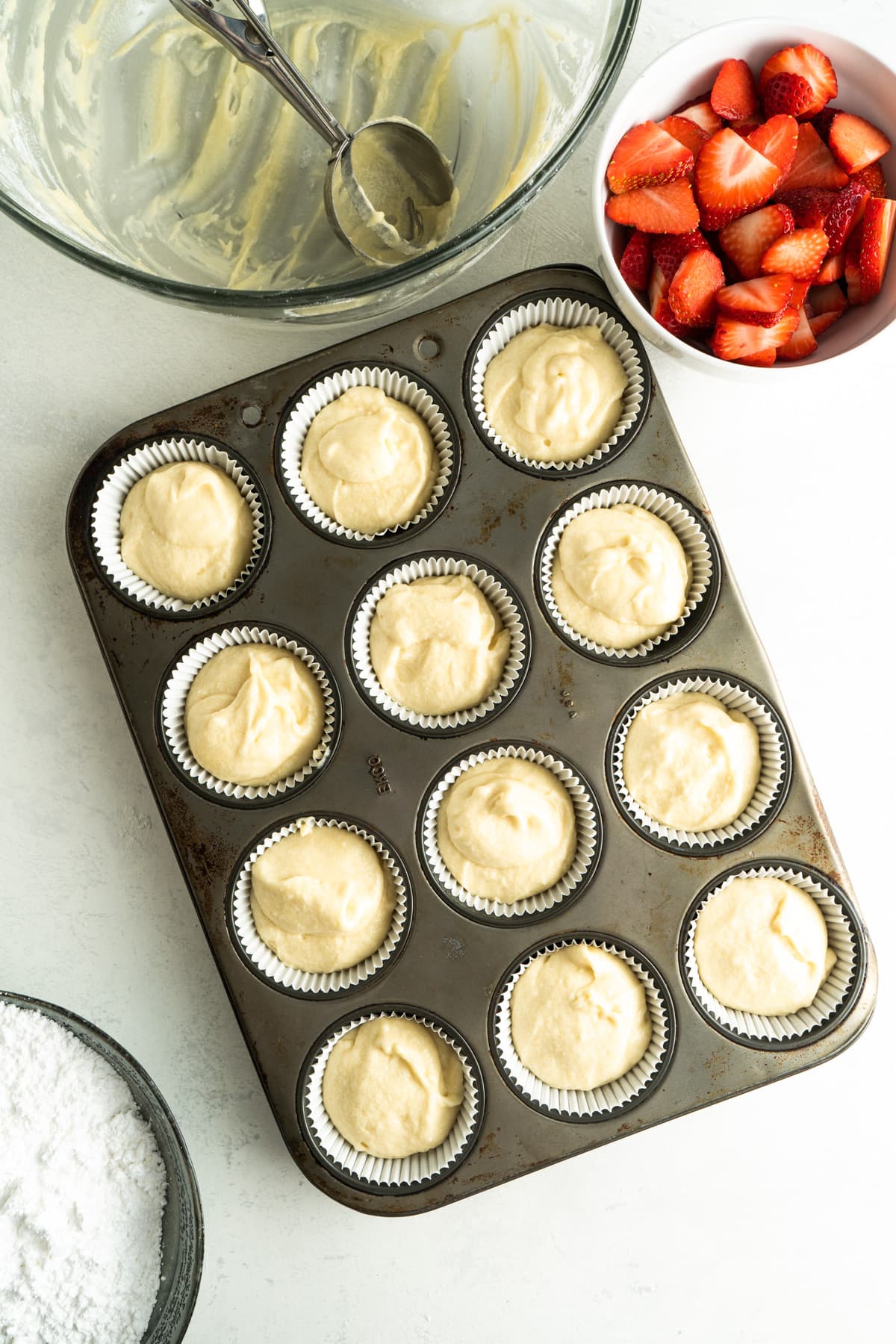 A muffin tin filled with a white chocolate cupcake recipe.