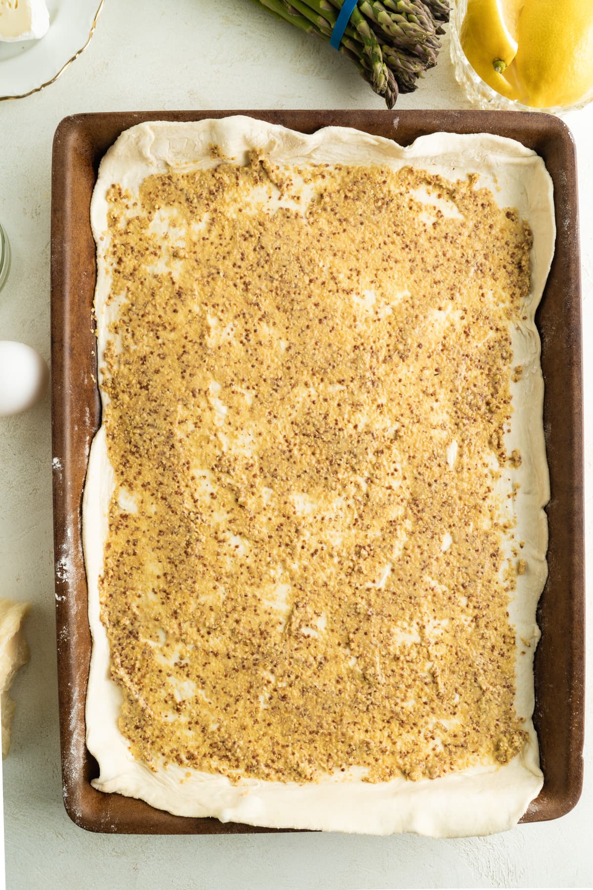 A sheet of puff pastry spread with dijon mustard.