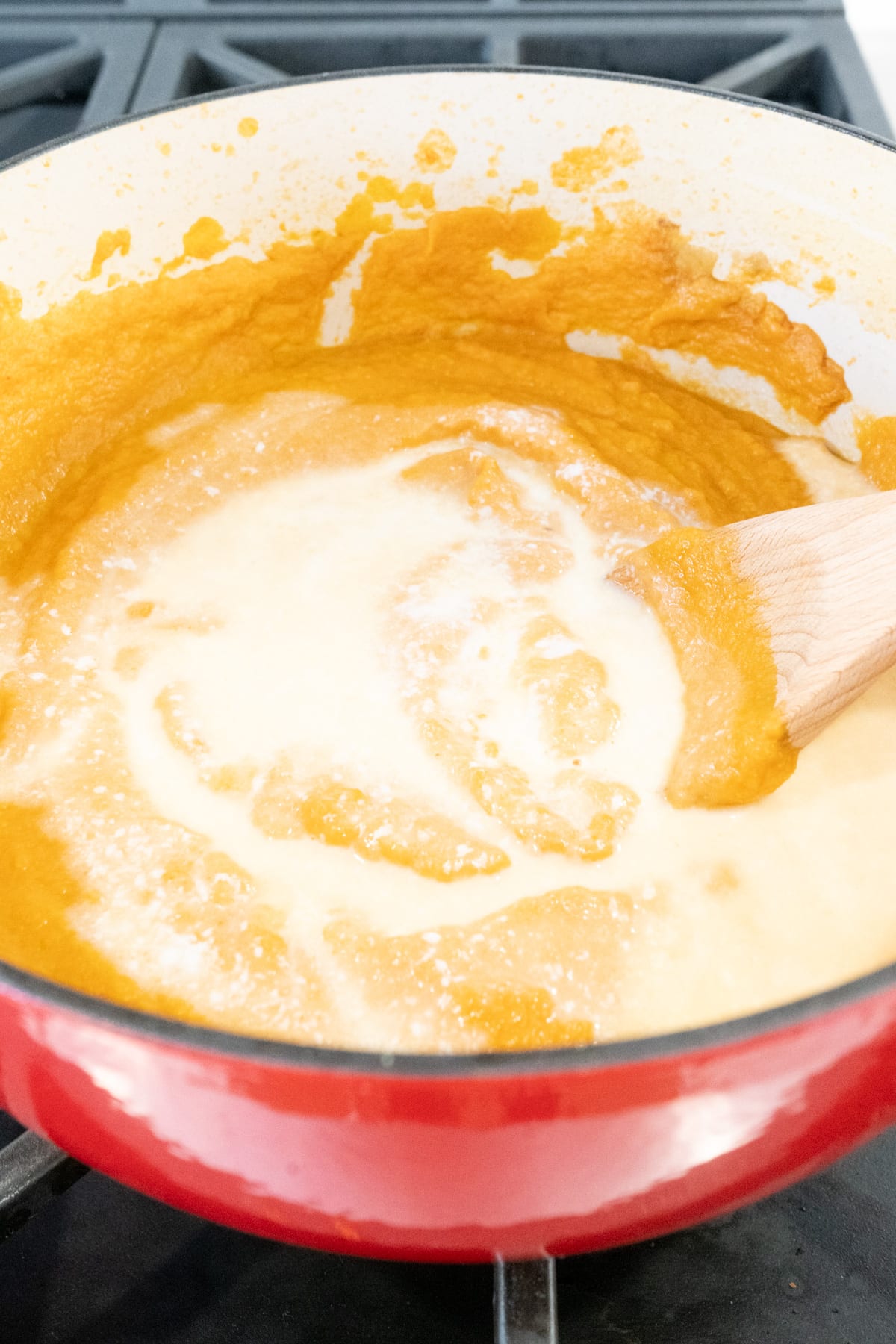 Cream being added to a pot of carrot gazpacho.