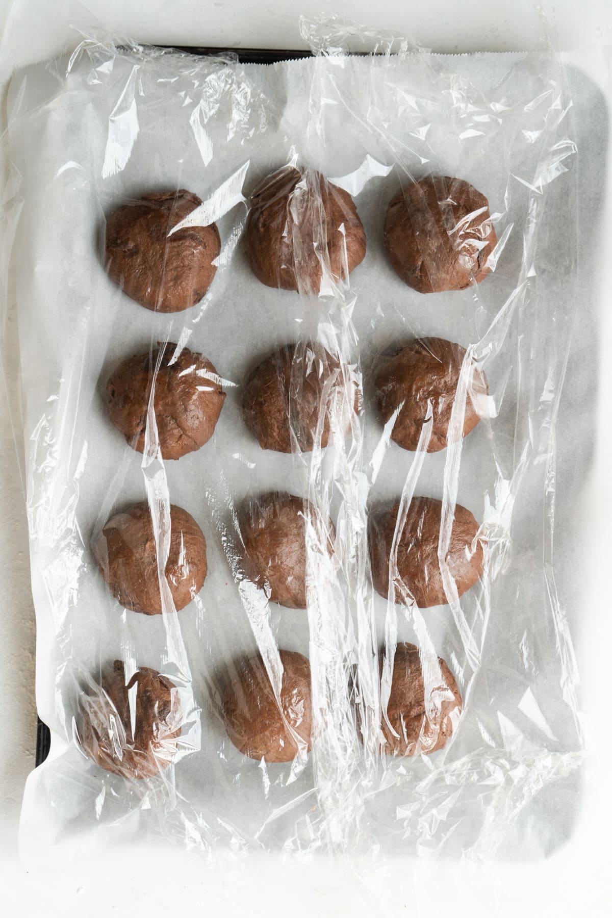 Formed buns on a baking sheet and covered to rise again.