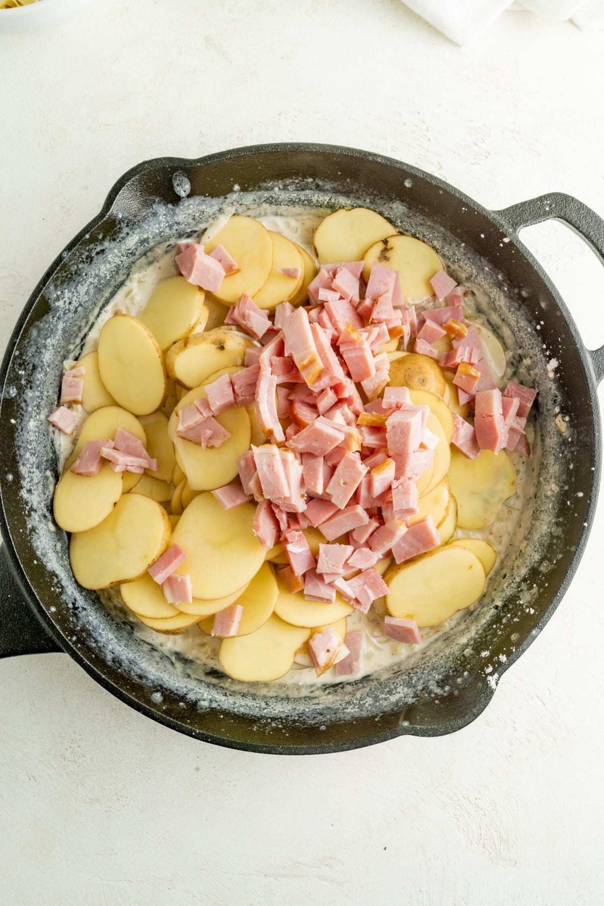A cast iron pan filled with potatoes and ham.