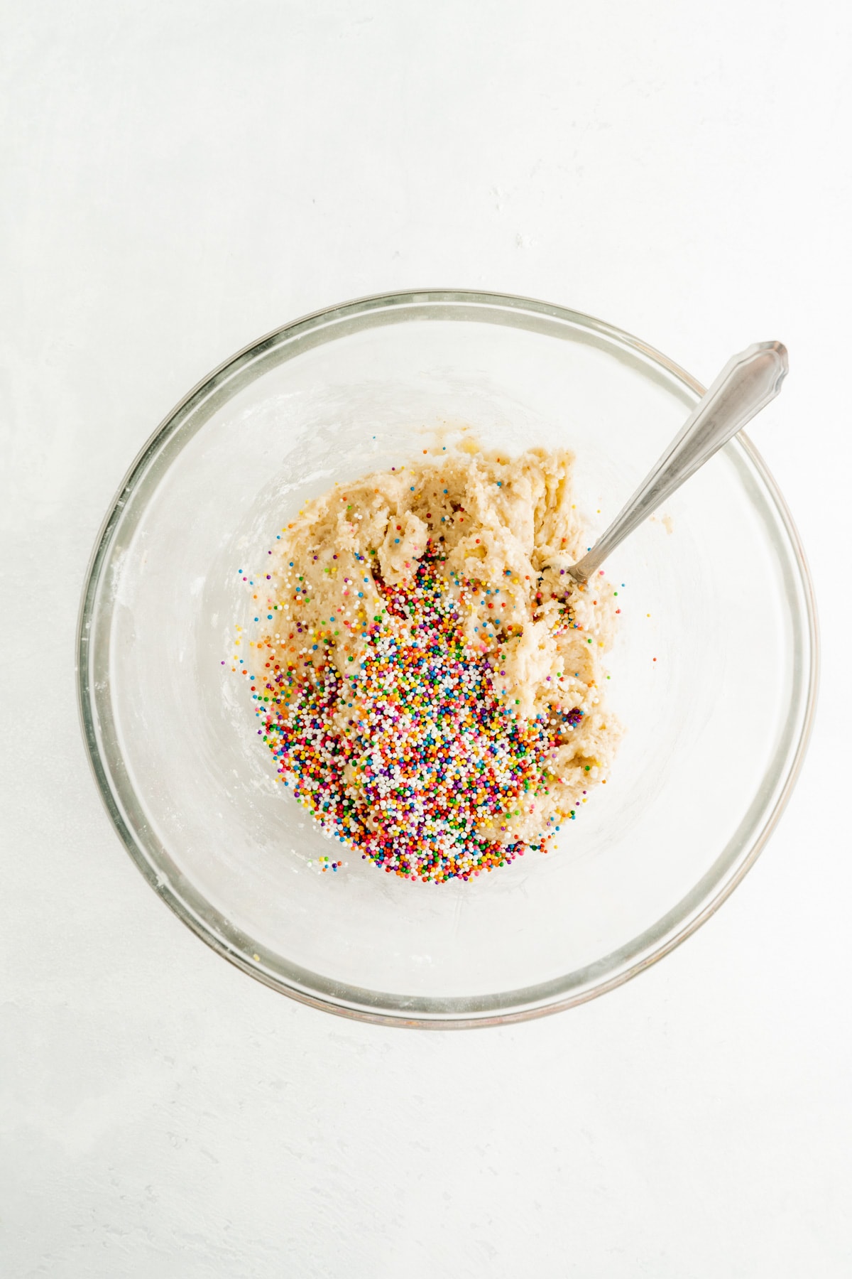 Confetti cake cookies batter in a bowl with sprinkles.