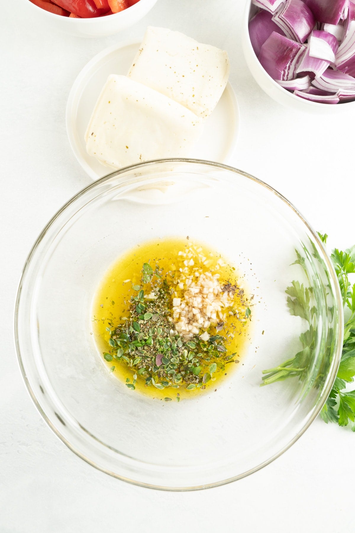 A bowl of olive oil, lemon juice, garlic and herbs.