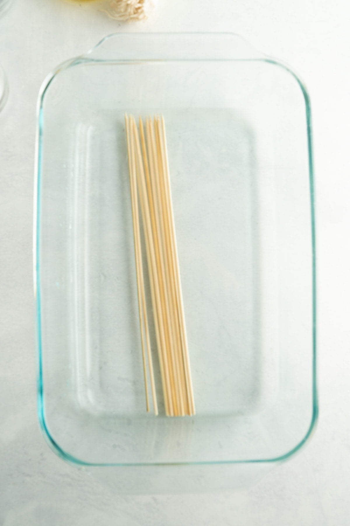 A dish filled with water and wooden skewers soaking.