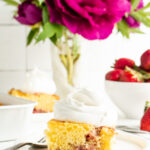 A slice of strawberry spoon cake on a table with flowers.