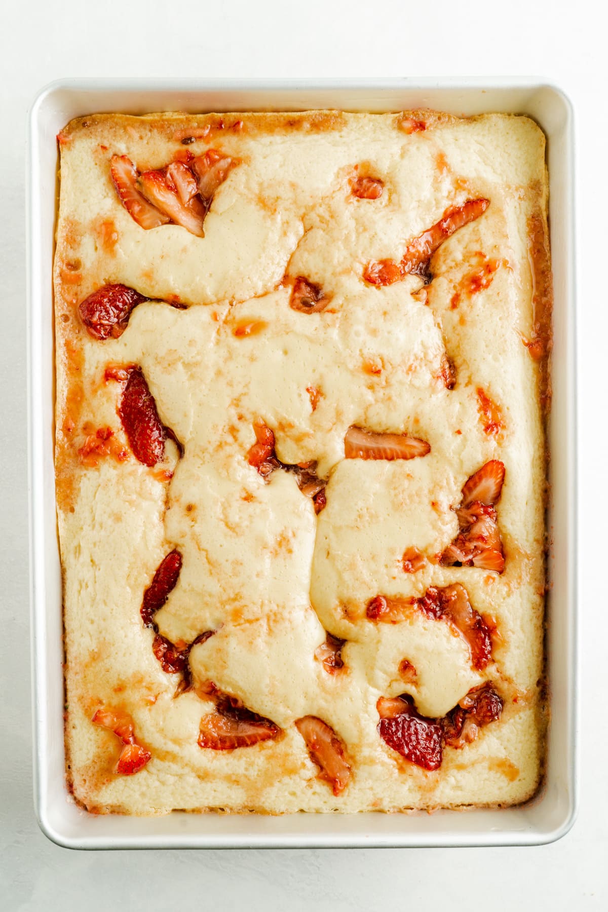 A vanilla sheet cake dotted with mascerated strawberries.