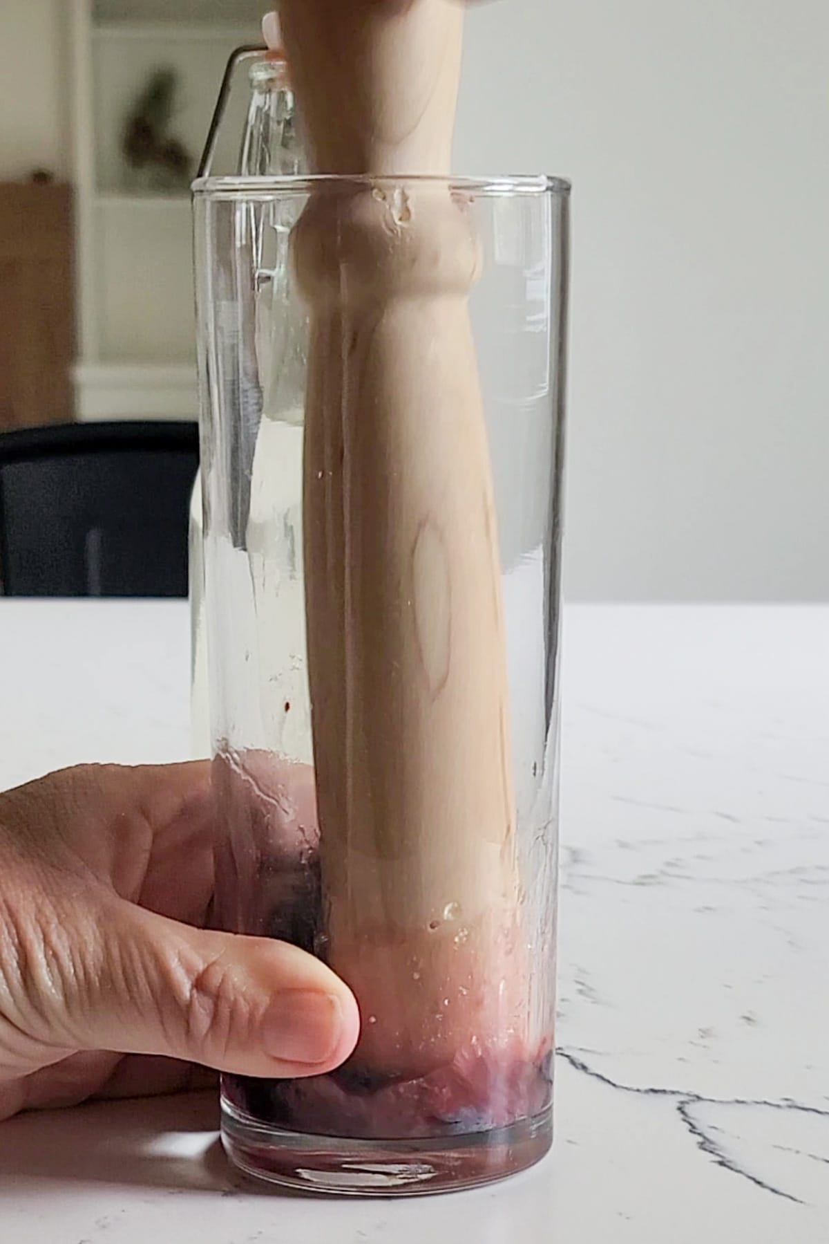 Muddling fresh blueberries in a tall glass