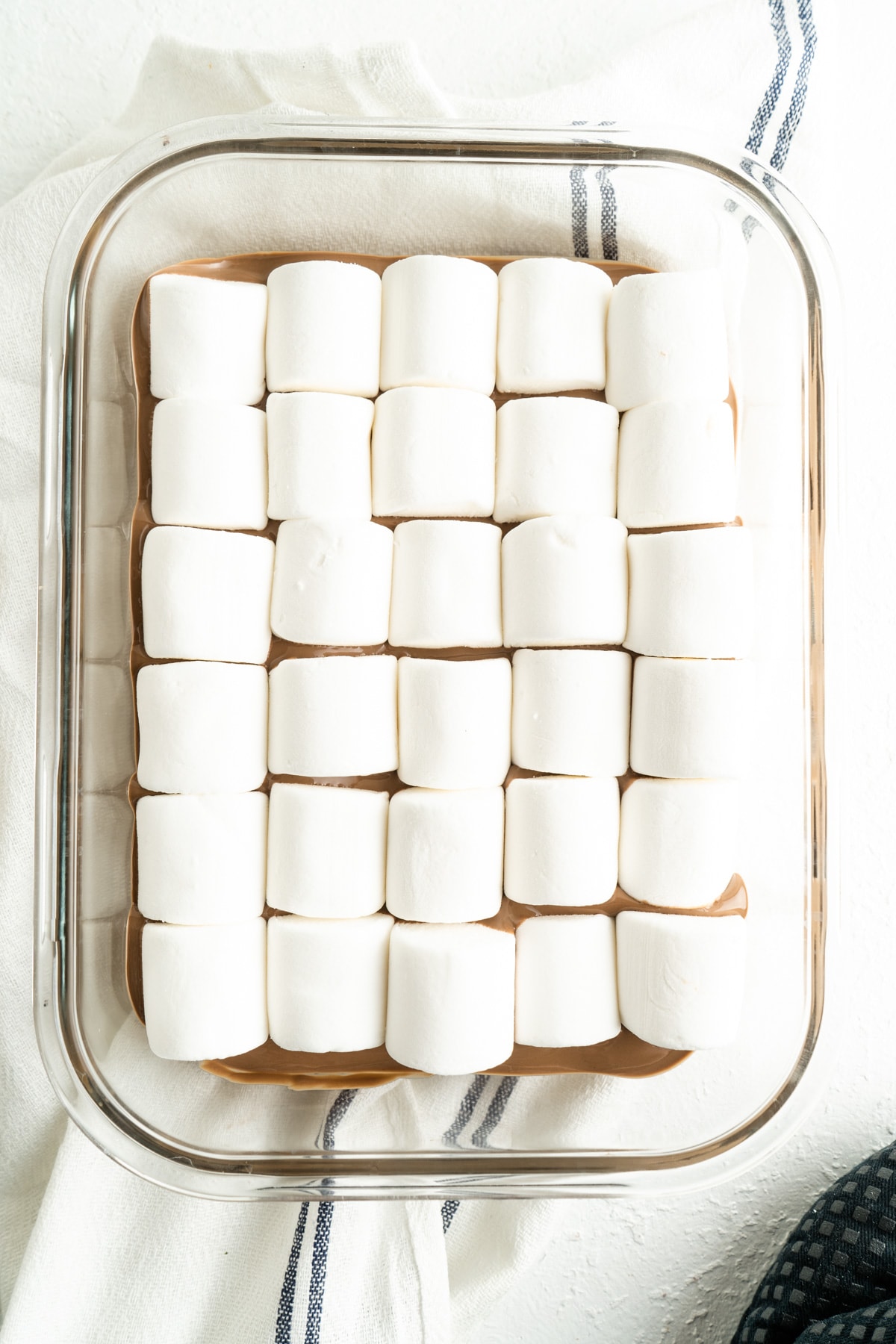 Marshmallows on top of a bed of melted chocolate for a smores dip recipe.