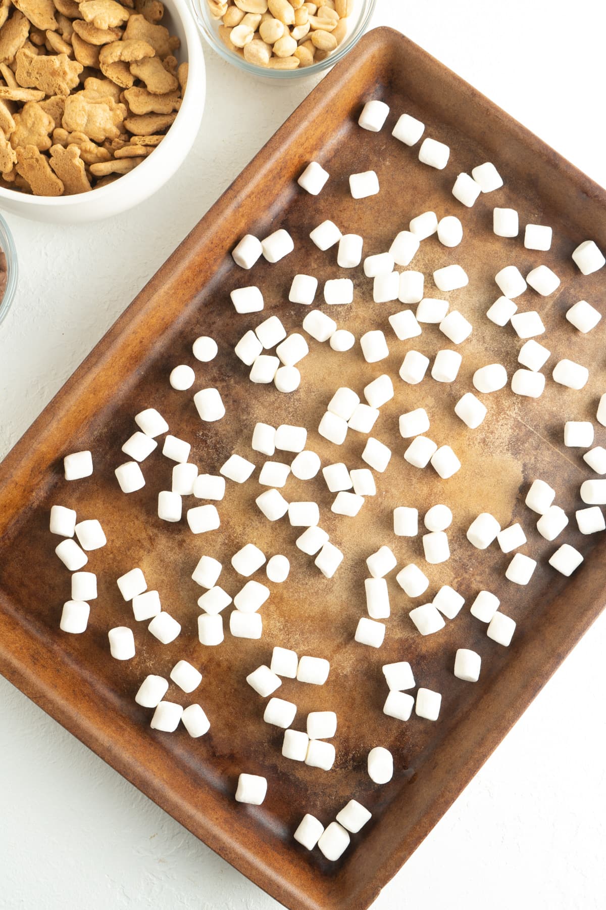 A baking sheet with mini marshmallows spread out.