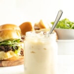 A jar of horseradish mayonnaise in front of roast beef sliders