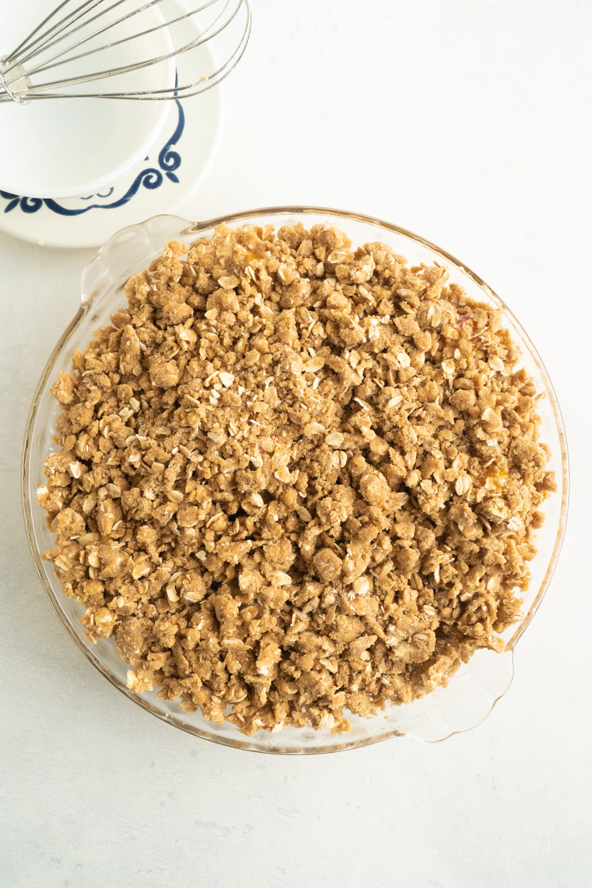 This Easy Peach Crumble features a fresh peach filling topped with a brown sugar and oat crumb topping. Enjoy with a scoop of ice cream! Overhead view of a pie dish of peach crisp