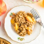 Overhead view of peach crisp on a plate next to a fork