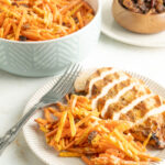 Carrot raisin salad on a plate with sliced chicken breast