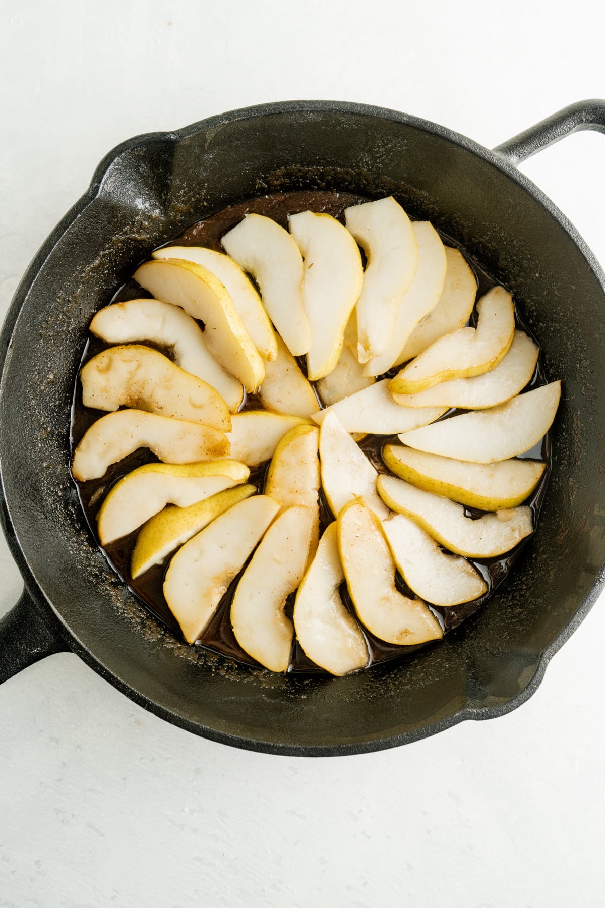 This Pear Upside Down Cake Recipe features a caramelized pear and brown sugar topping over a sweet, tender cake. Pear slices arranged in a skillet
