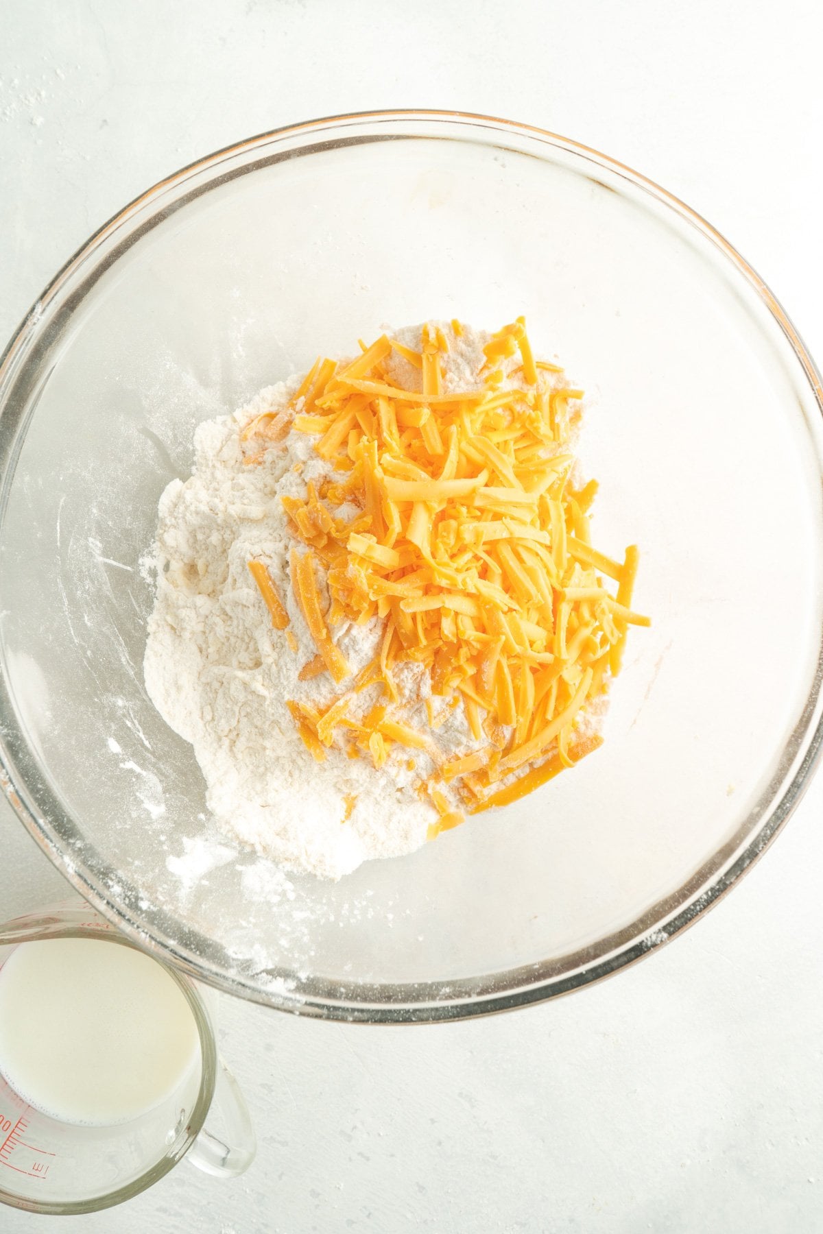 Cheese on top of flour in a glass bowl.