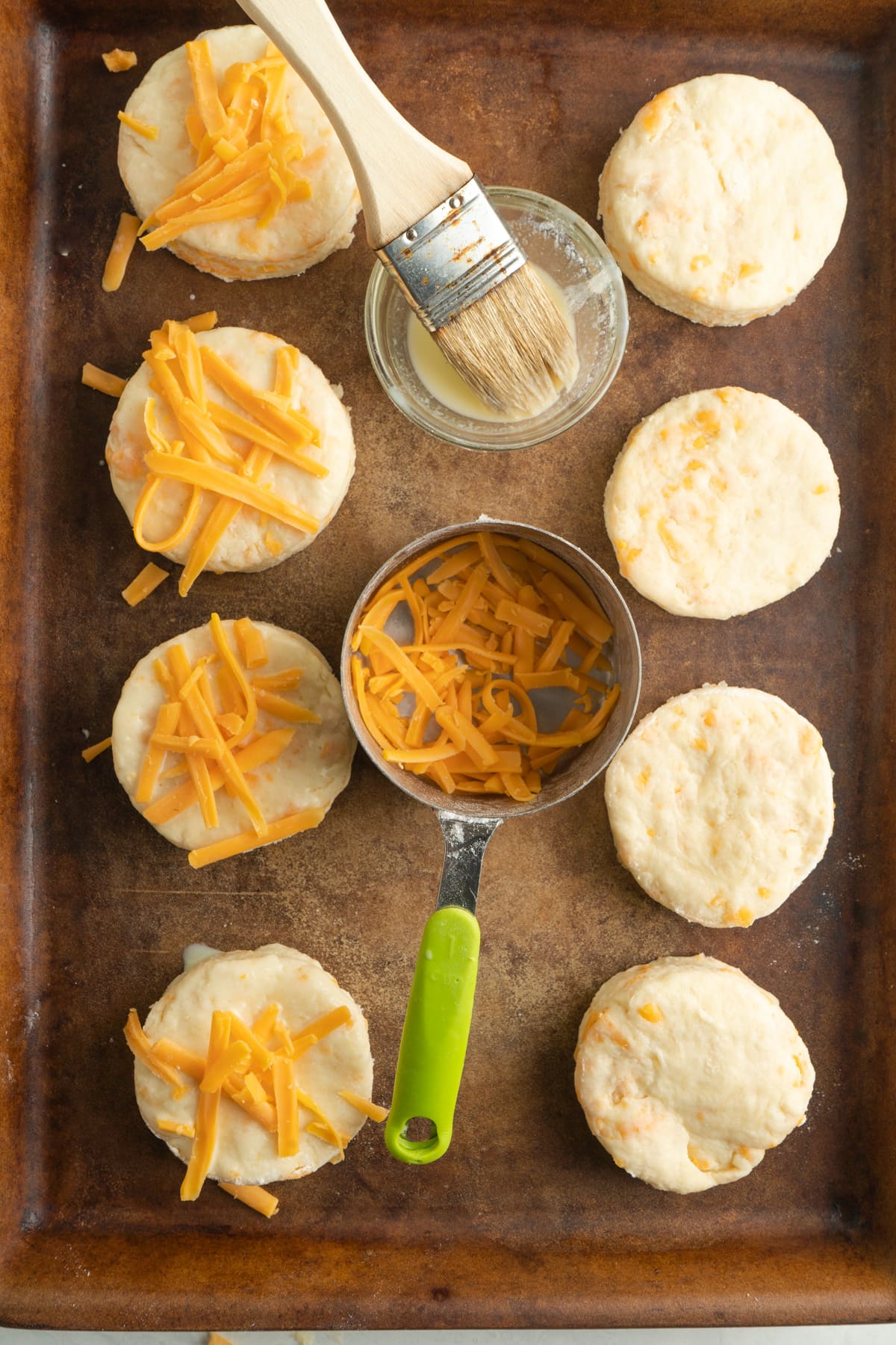 Cheese in a pot between raw buttermilk scones on a baking sheet.
