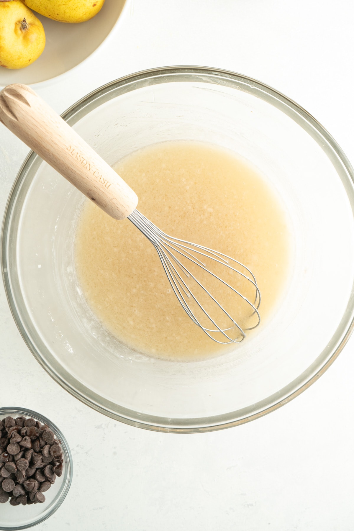A whisk in a bowl of wet cake batter ingredients
