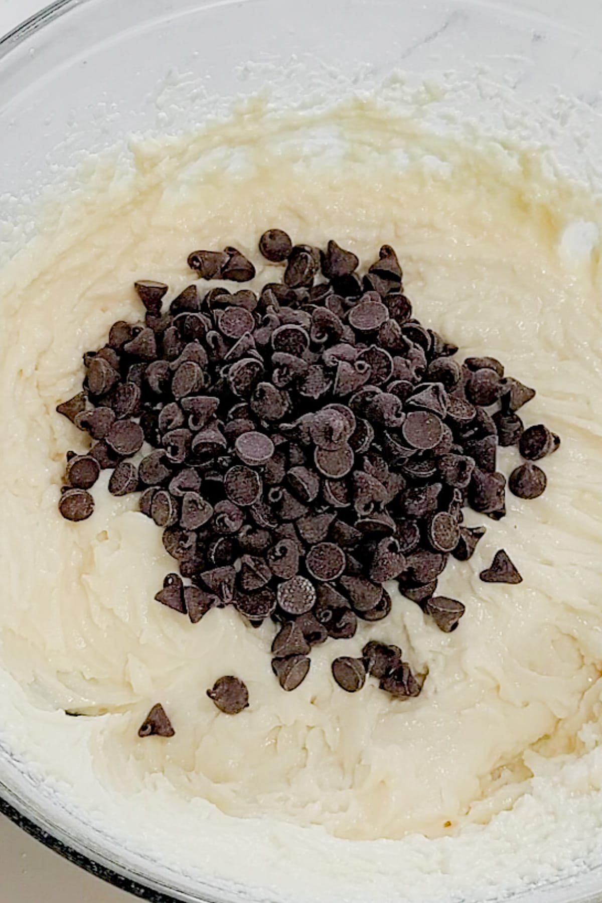 Chocolate chips added to the mixing bowl of cannoli dip.
