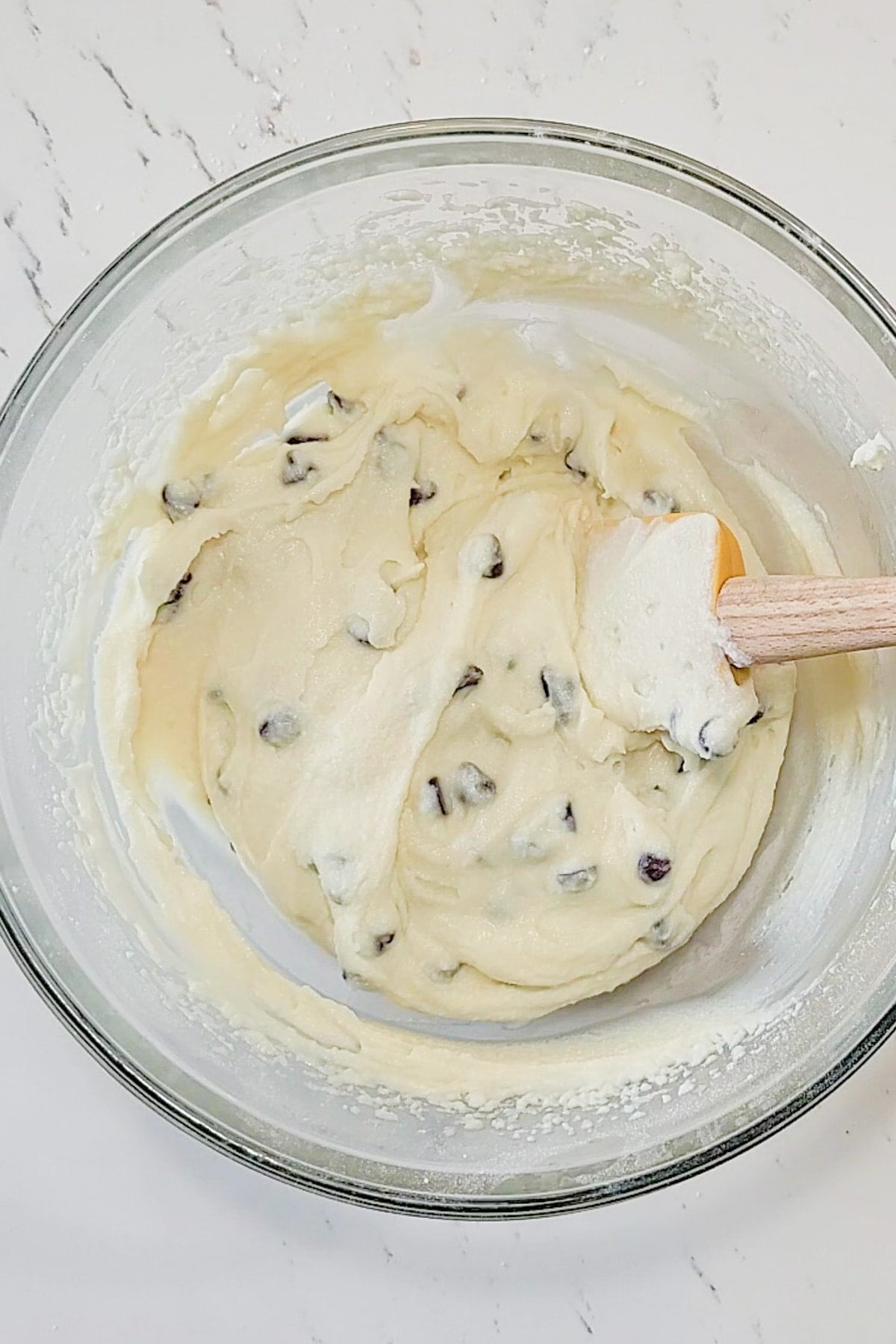 A spatula stirring an Italian cannoli dip recipe in a bowl.