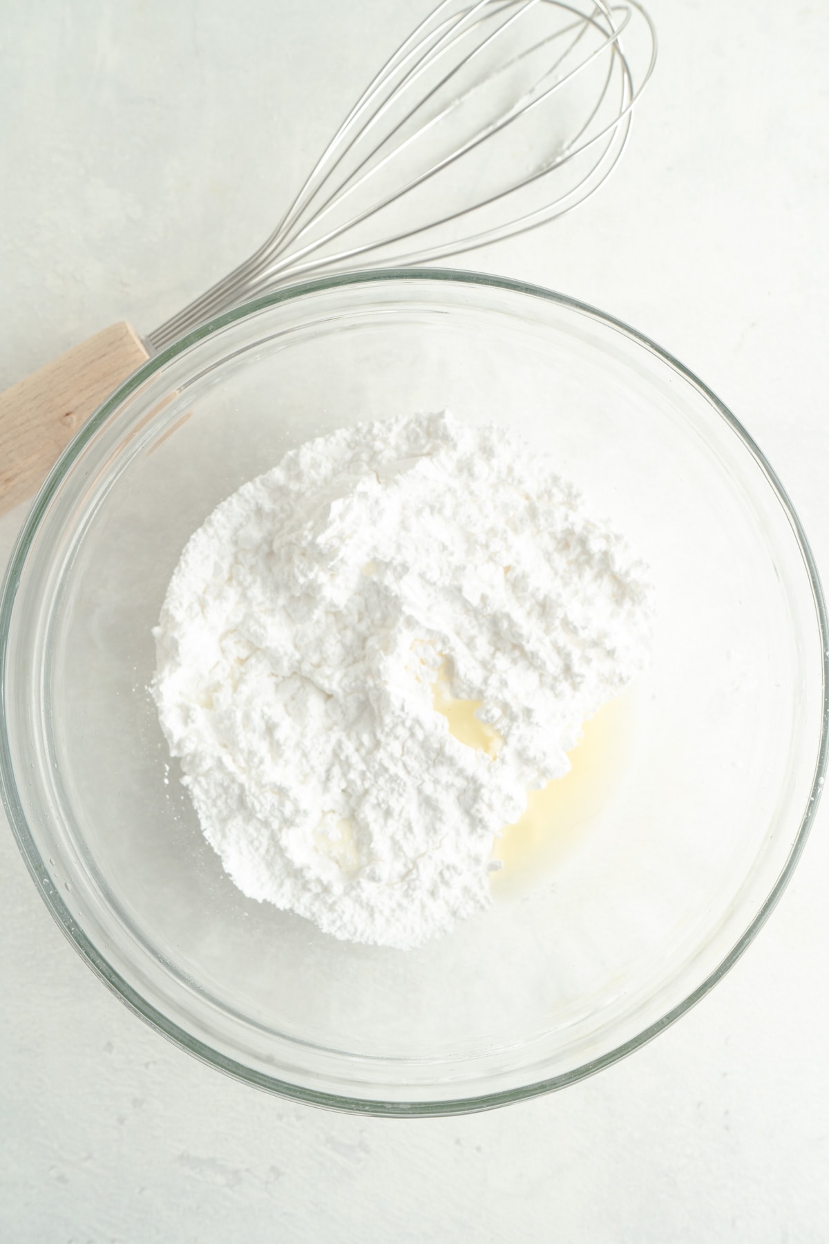 A bowl of icing sugar and lemon juice with a whisk.
