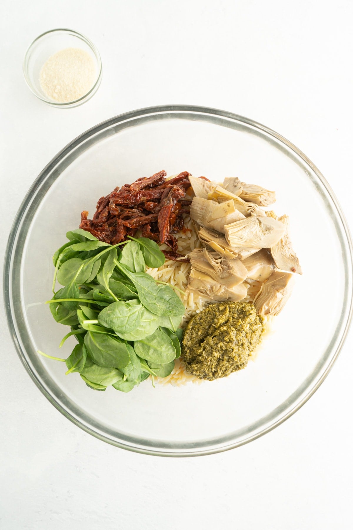 Ingredients for an orzo pasta salad with spinach and peso in a bowl.