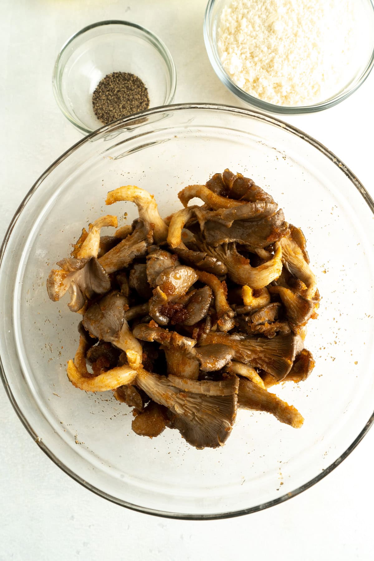 Oyster mushrooms being marinated in a bowl with a paprika rub.