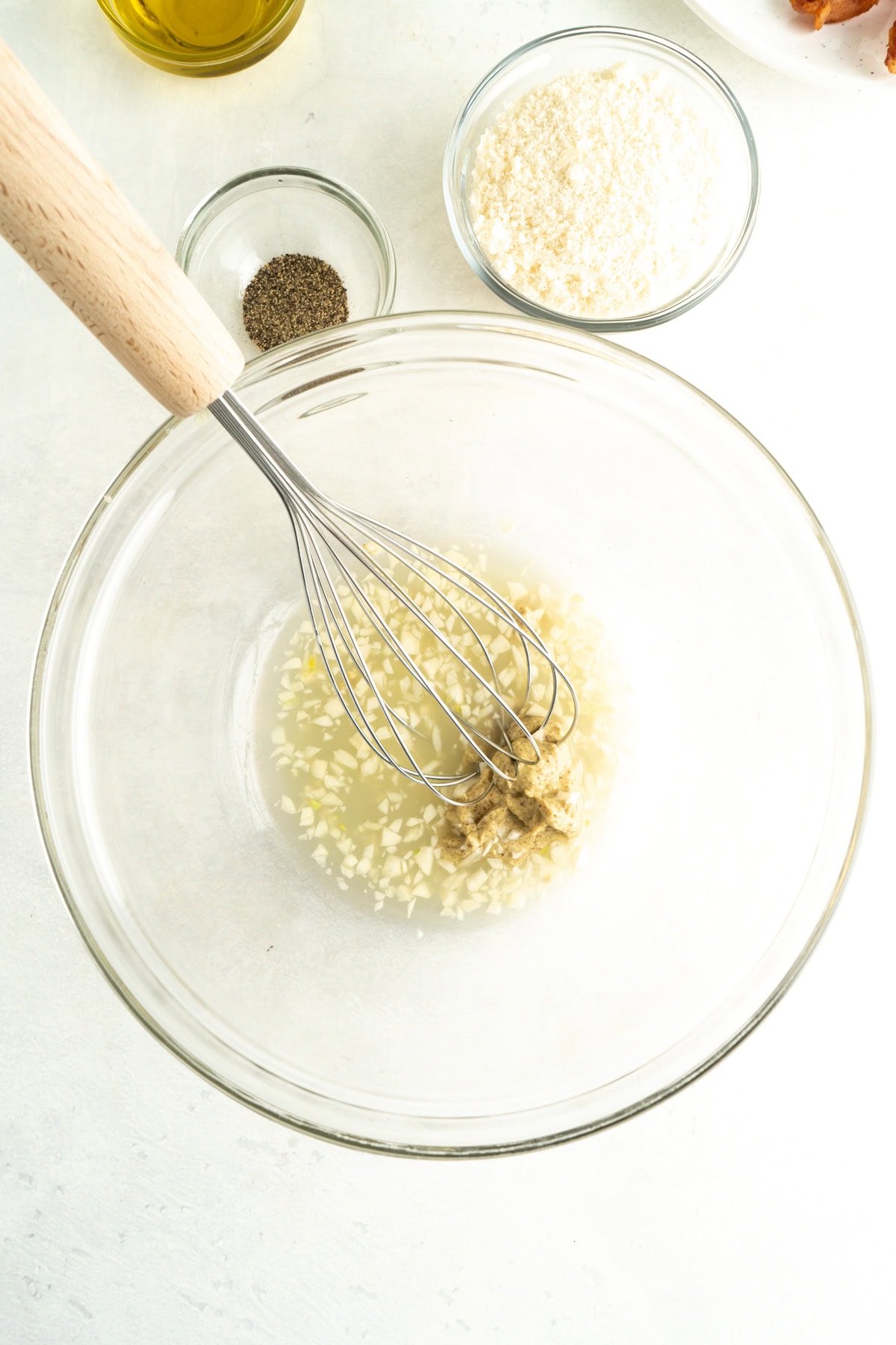 Garlic, mustard and lemon juice in a bowl with a whisk.