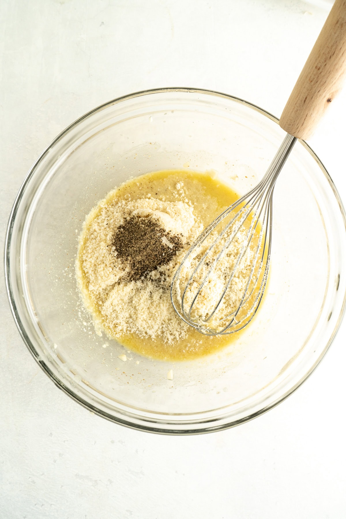Ingredients in a bowl for a salad dressing with a whisk.