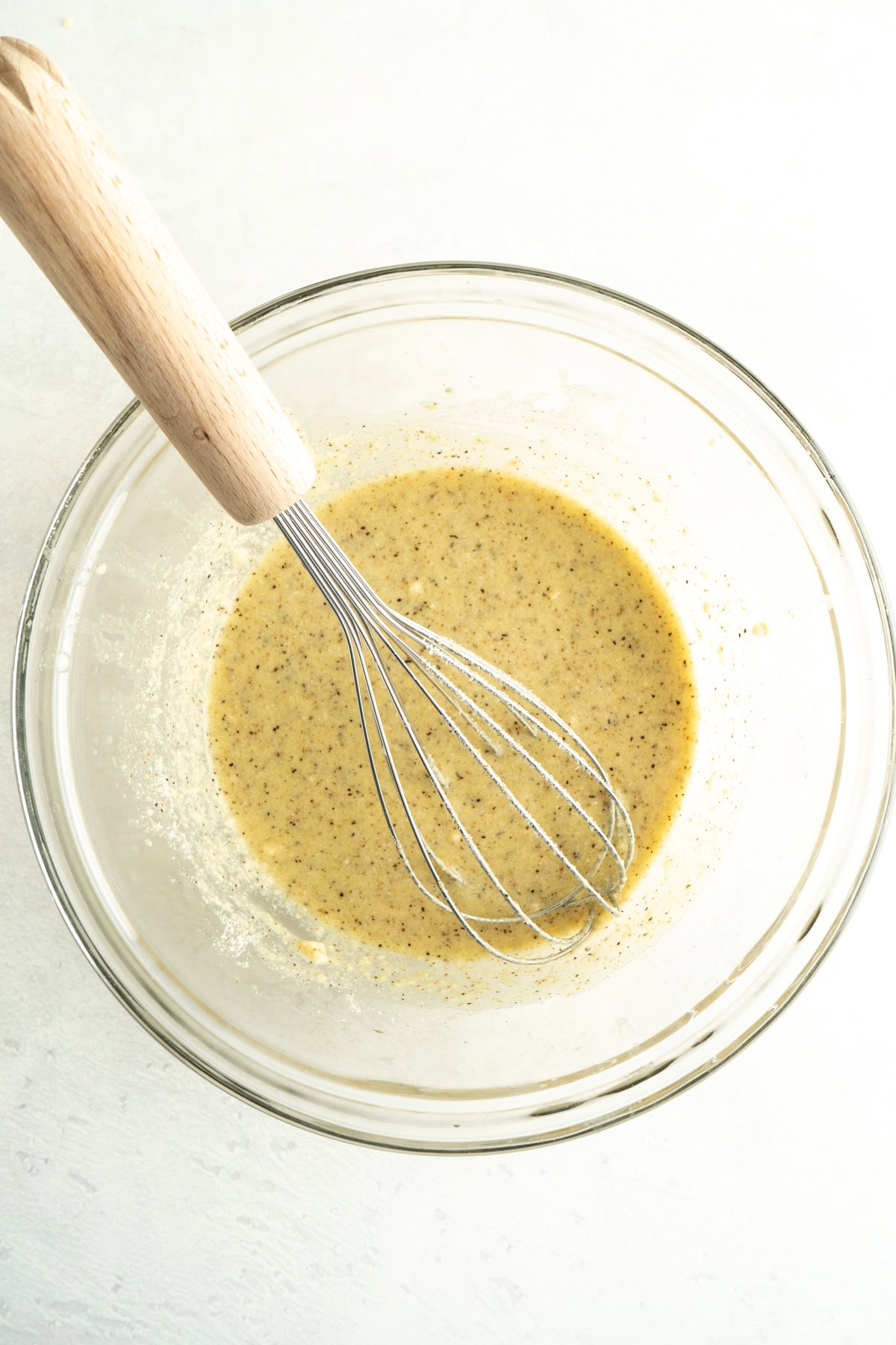 Cesar salad dressing in a bowl with a whisk.