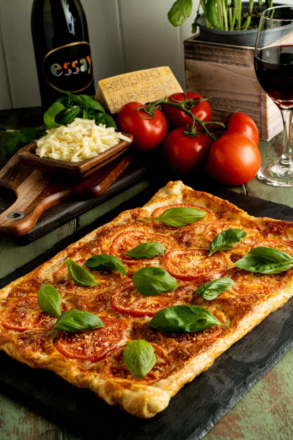 Tomato basil tart on a table with red wine.