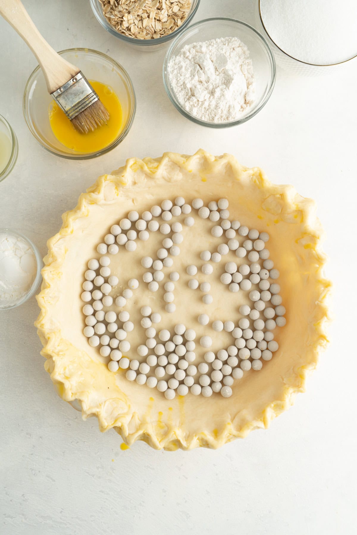 A pie crust in a pie pan that has been fluted and filled with pastry beats prior to baking.