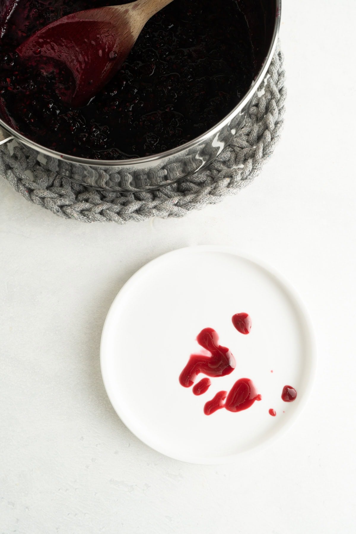 A drizzle of homemade blackberry jam on a chilled saucer to check the set point.