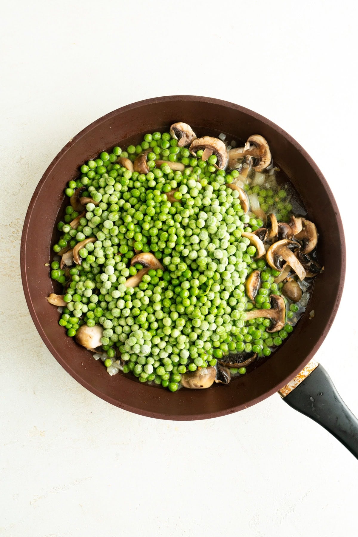 Peas and mushrooms in a pan.