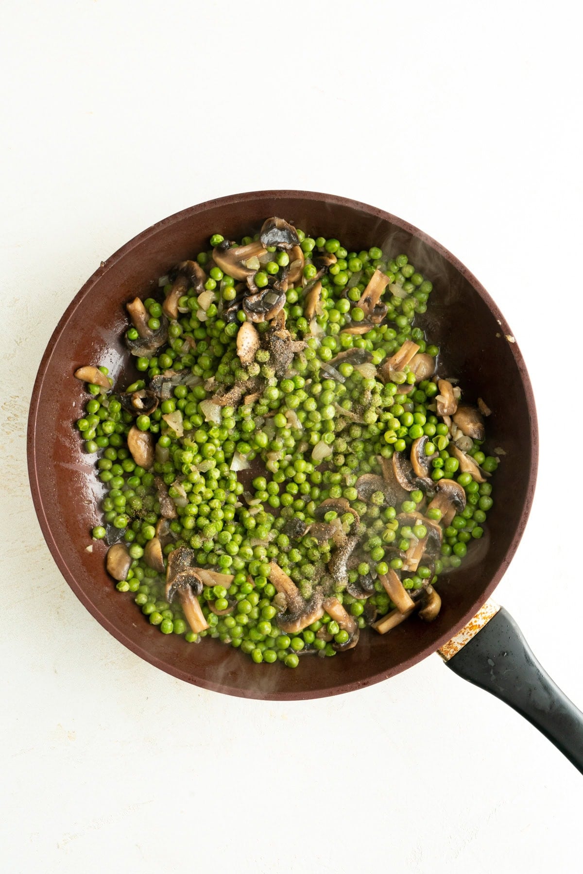 Mushrooms and peas in a pan with water.