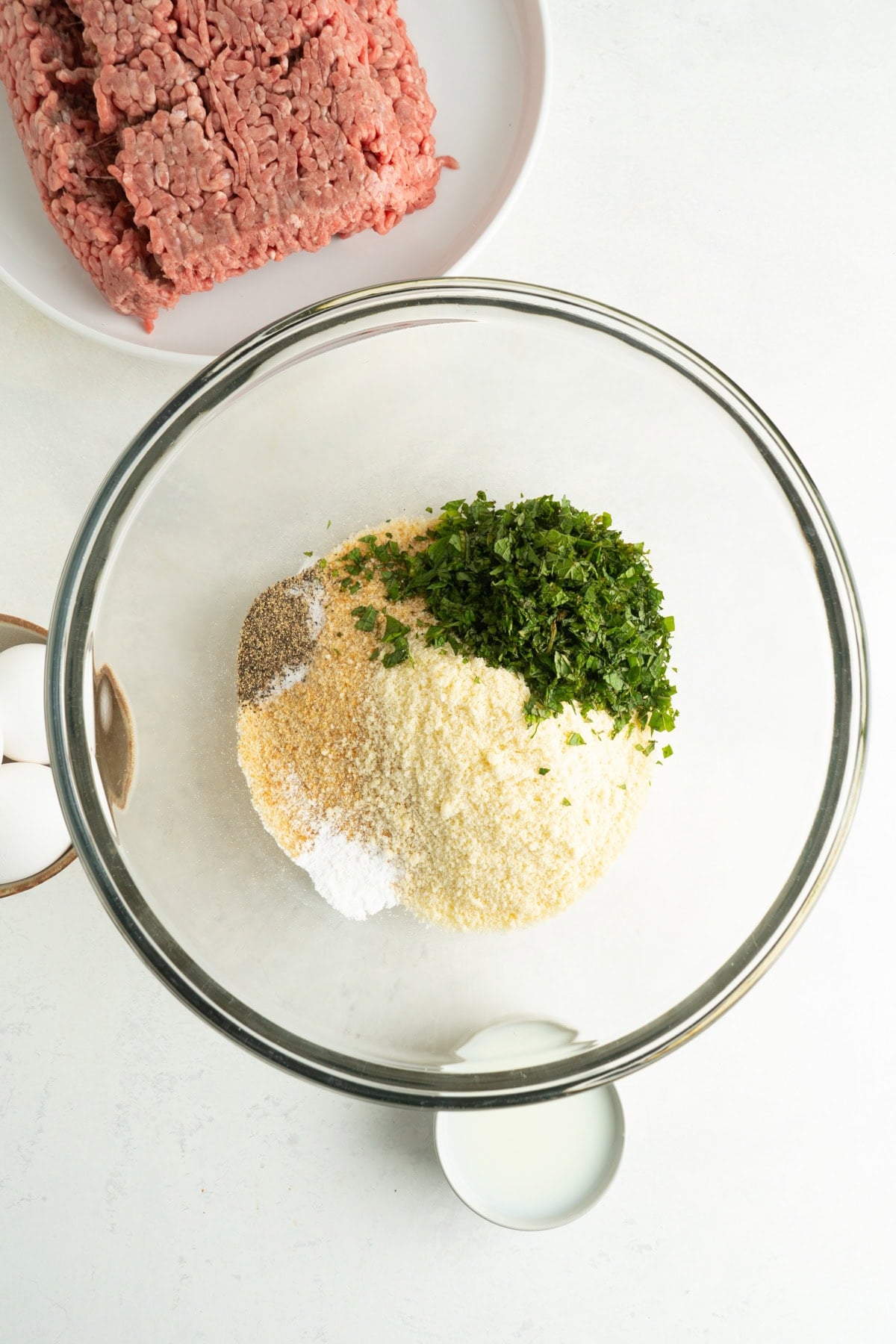 Parmesan, bread crumbs, mint and seasoning in a bowl for traditional Italian meatballs.