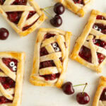 Cherry Hand pies on a table with eyes to turn them into mummies for a Halloween treat.