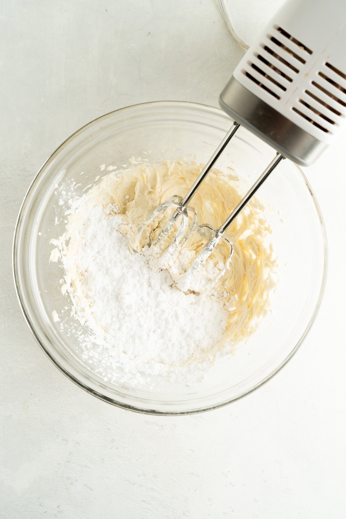 Cream cheese filling ingredients in a bowl with a hand mixer.