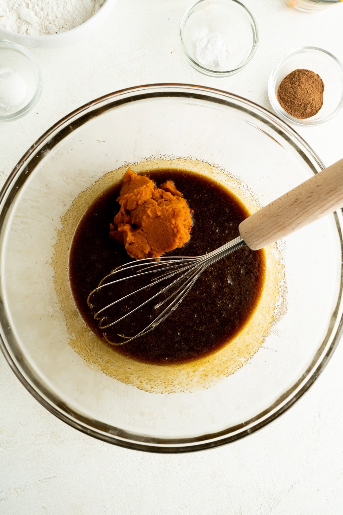 Pumpkin being added to a mixing bowl for cookies.