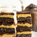 Two towers of Nanaimo bars stacked 3 high on a table at tea time.