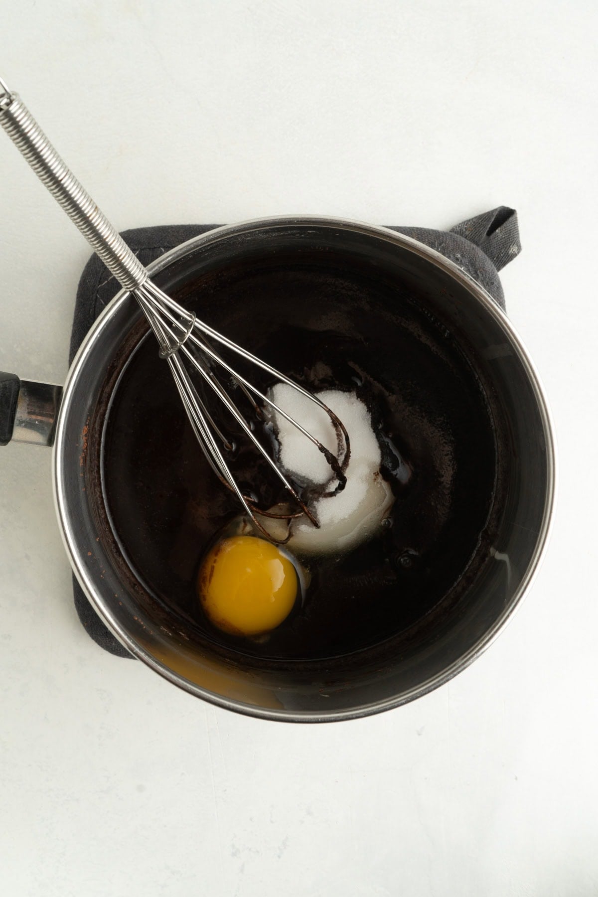 A pot of melted chocolate and and egg and sugar being whisked to blend.