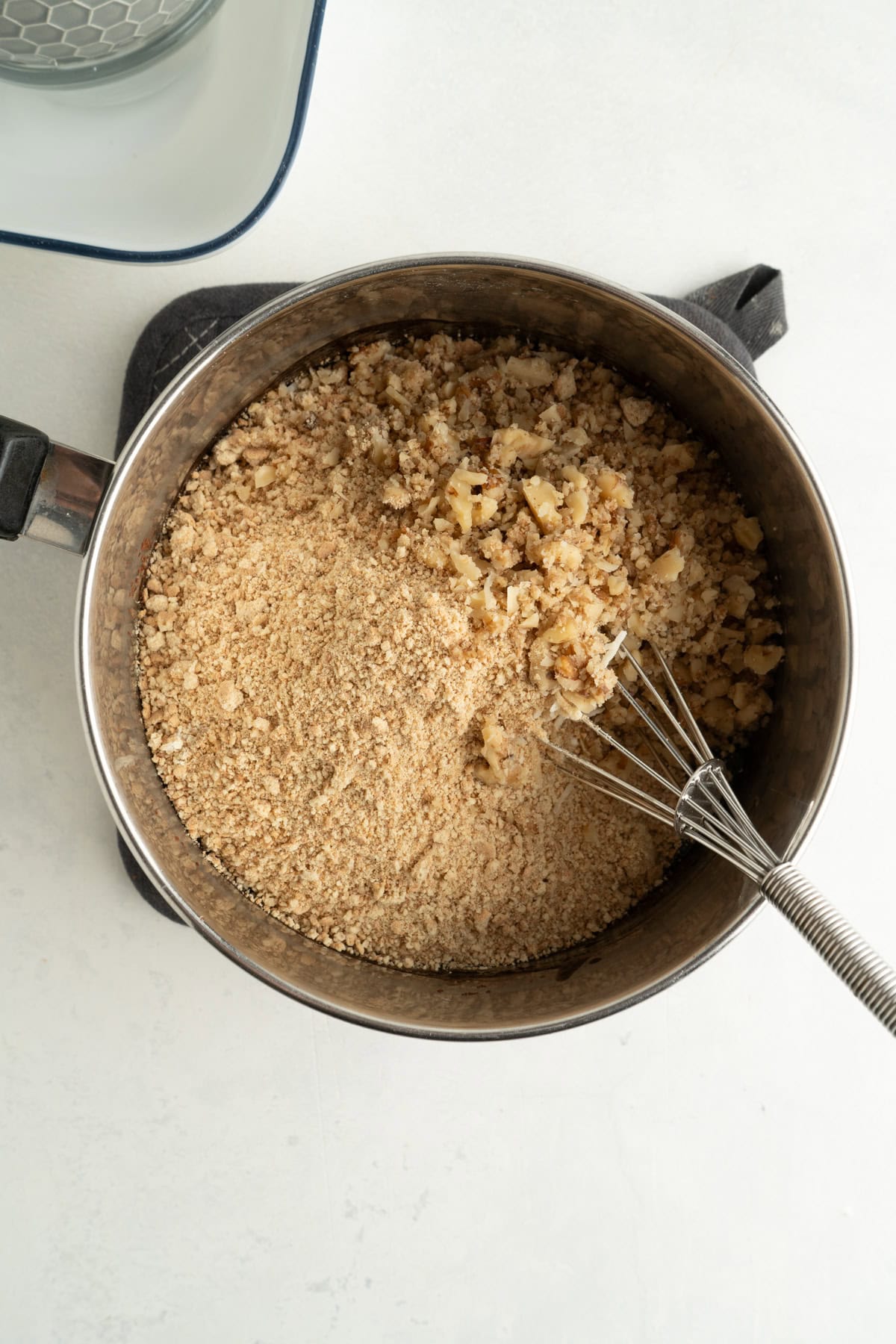 A large pot filled with graham crackers, coconut and walnut being mixed into melted chocolate.