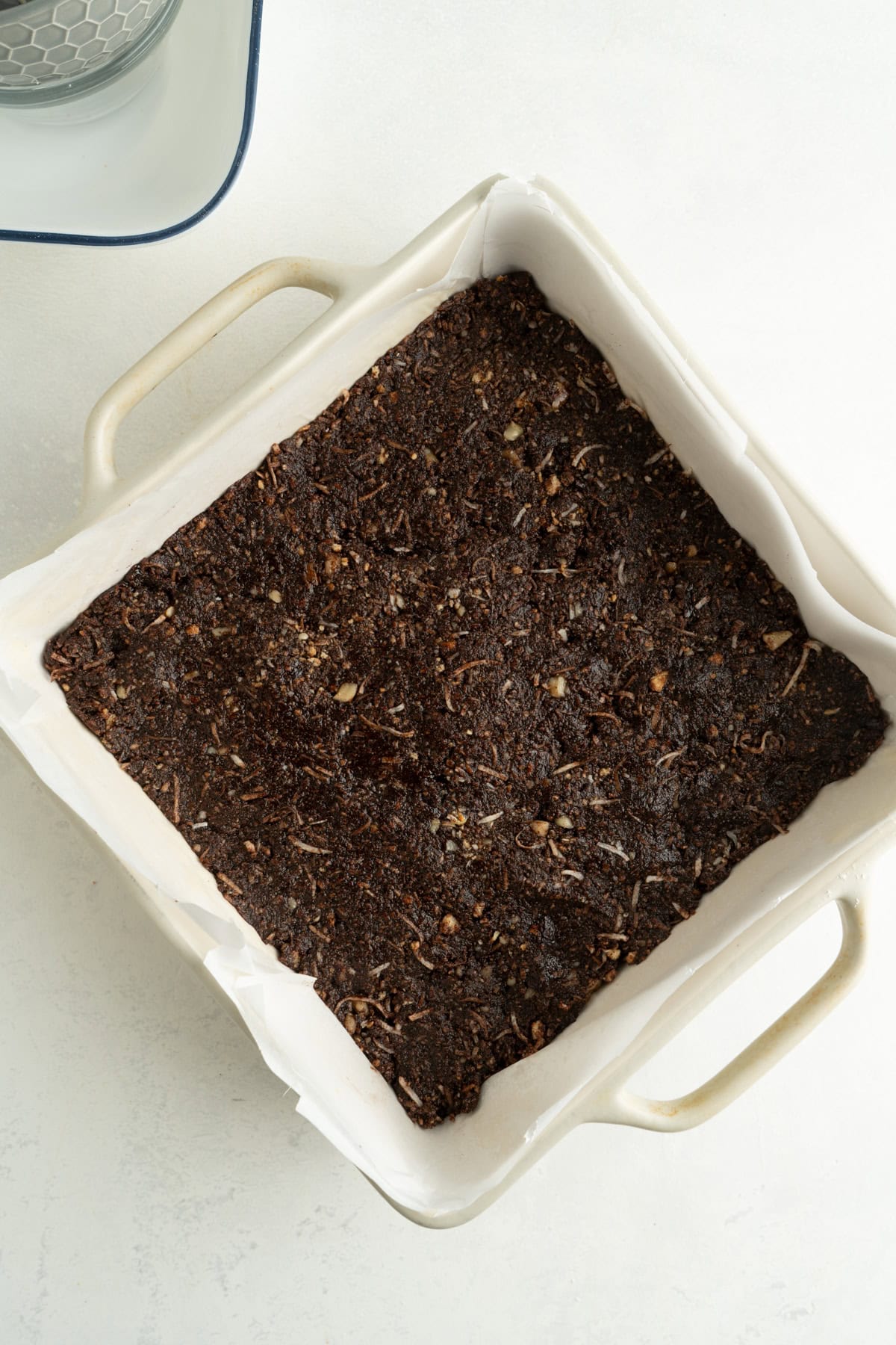 The chocolate and coconut base for nanaimo bars in a square pan.