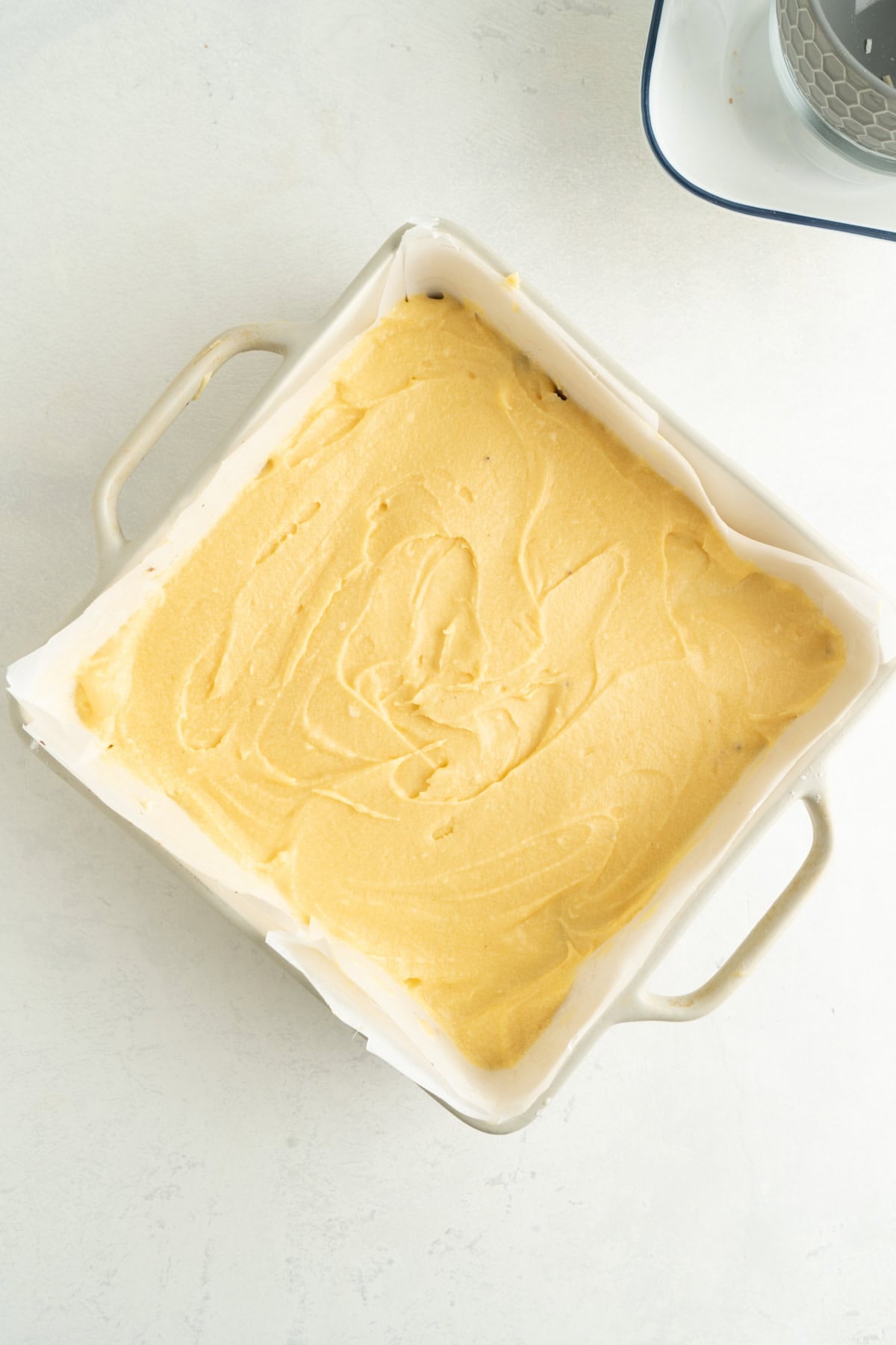 A custard cream layer for Nanaimo Bars in a square pan.