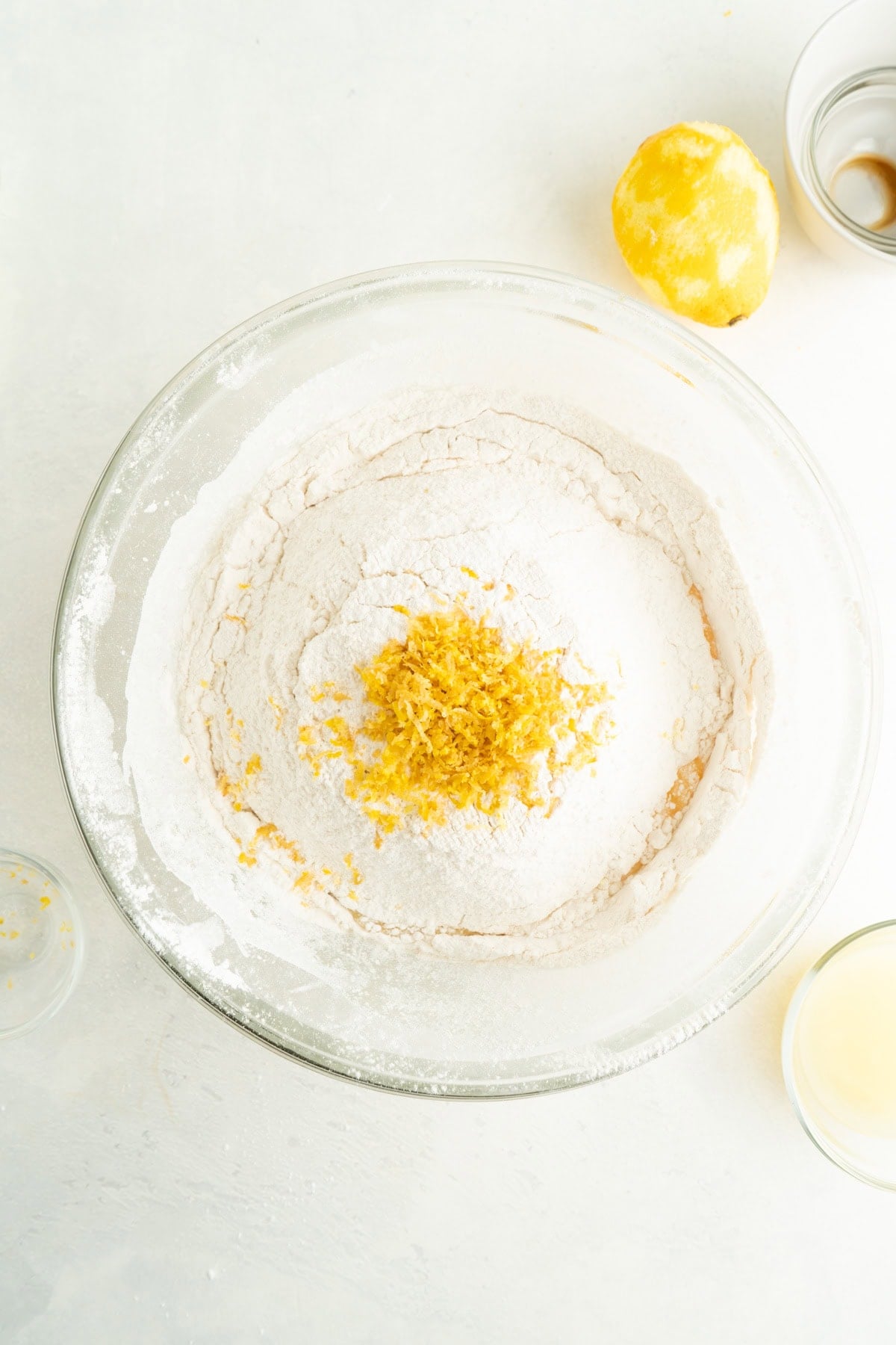 A bowl of sugar and lemon zest being added to an egg mixture.